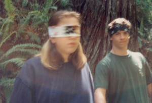 A woman with a blindfold on and another man standing next to her.