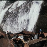 A group of people standing on top of rocks near a waterfall.