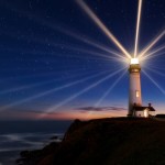 A light house shines at night on the top of a hill.